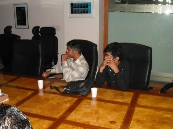 Two people seated at a boardroom table in an early photo