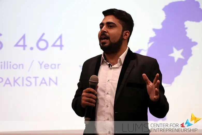 Speaker on stage in front of a slide with a map of Pakistan