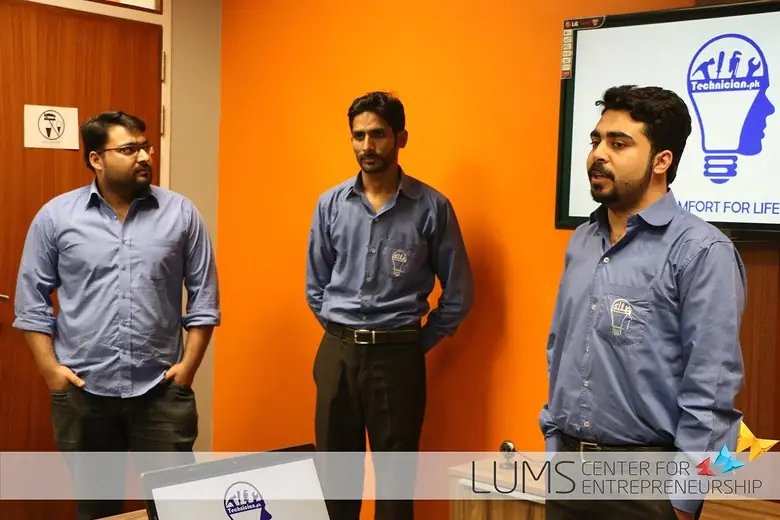 Three team members in matching shirts presenting Technician.pk