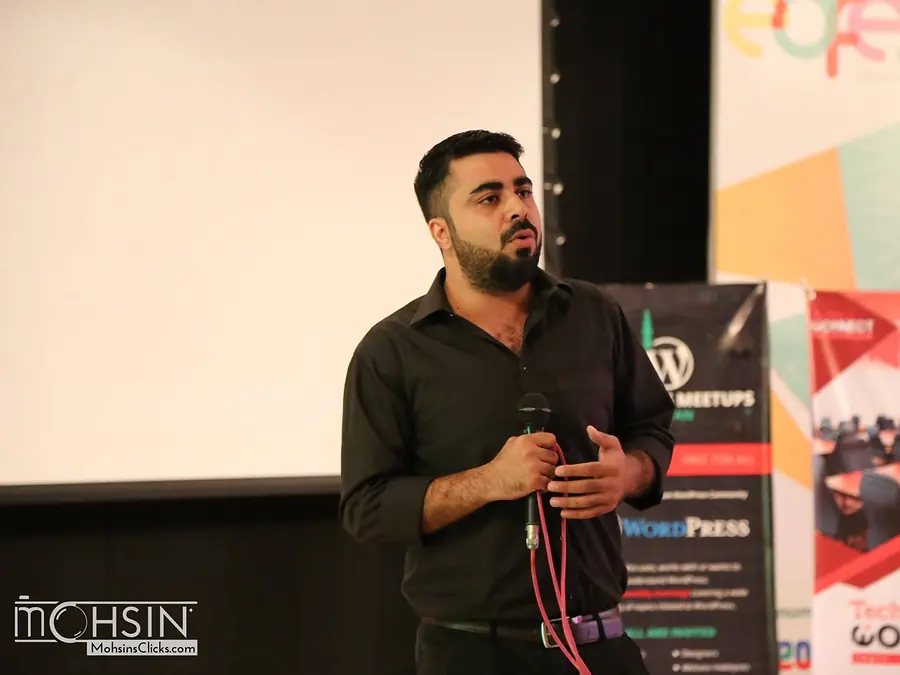 Speaker with a microphone beside WordPress Meetups Pakistan and TechHub Connect banners